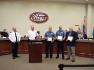 Group of five standing at podium holding certificates