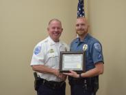 Younger blonde officer with beard holding certificate and shaking another officers hand