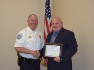 Man in suit holding certificate and shaking an officers hand